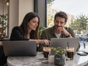 Two freelancers in front of their computers working in a cafeteria