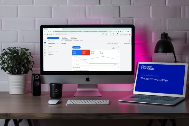 Desktop setup showing Google Ads performance dashboard alongside a Knowcrunch digital advertising strategy presentation.