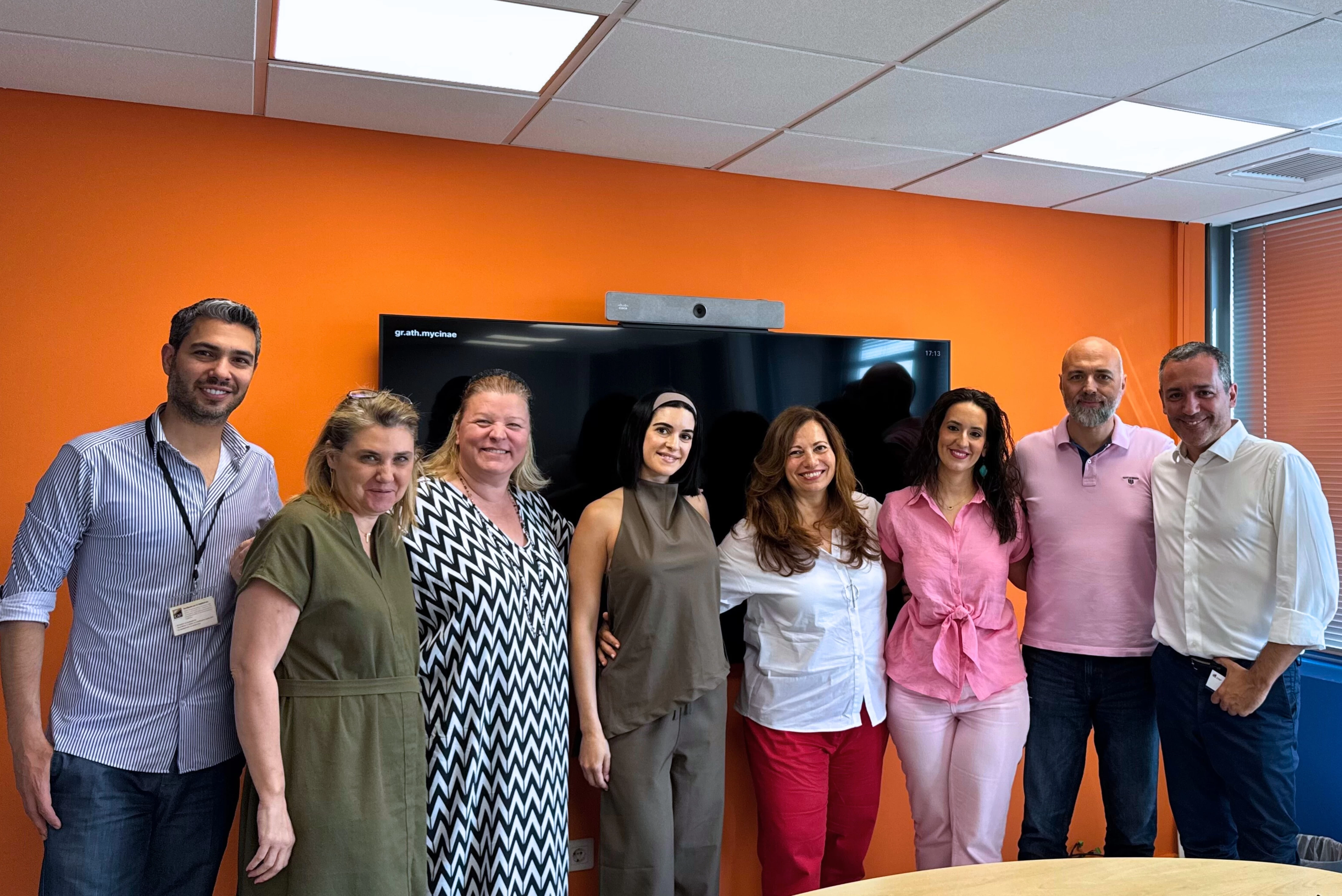 Group photo of ICAP CRIF and Knowcrunch team members standing in front of a screen in a brightly lit meeting room with an orange wall, taken during LinkedIn corporate training sessions.